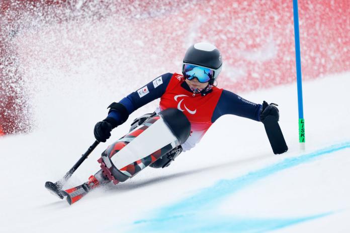 A female Para alpine skiing athlete is racing down the slope on a sit-ski